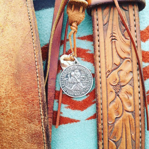 St. Christopher hanging from a saddle over a light blue and red saddle blanket